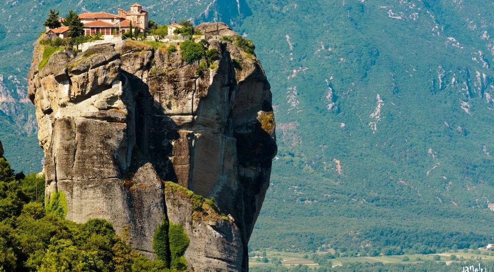 Обои для рабочего стола Монастырь Agia Triada, Meteora, Greece / Метеора, Греция на вершине отвесной скалы, освещенный солнцем, на фоне размытых поросших лесом гор