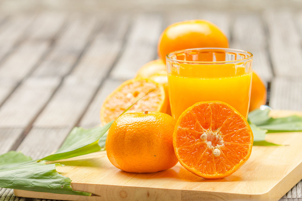 Обои для рабочего стола Апельсиновый сок в стакане среди апельсиновых долек
