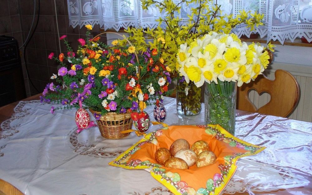 Обои для рабочего стола Тарелка с пасхальными яйцами и два букета цветов на столе