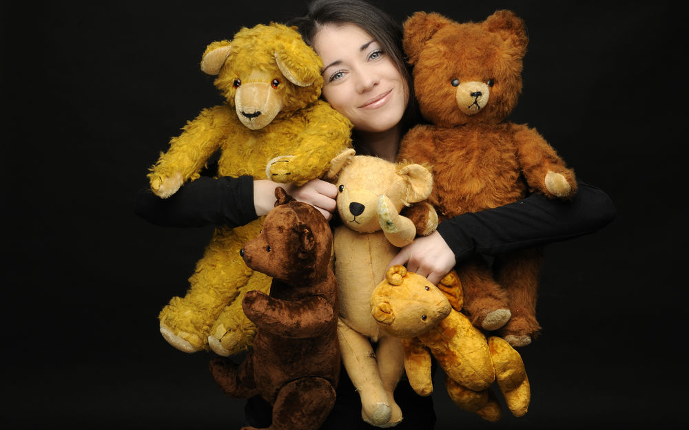 Обои для рабочего стола Улыбающаяся девушка с разноцветными игрушечными медведями