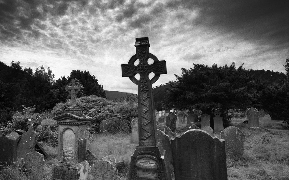 Обои для рабочего стола Старое кладбище в черно-белых тонах на фоне затянутого тучами неба