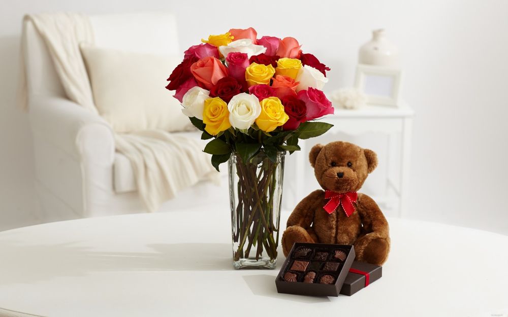 Обои для рабочего стола Букет разноцветных роз в вазе, плюшевый медведь и коробка конфет на столе