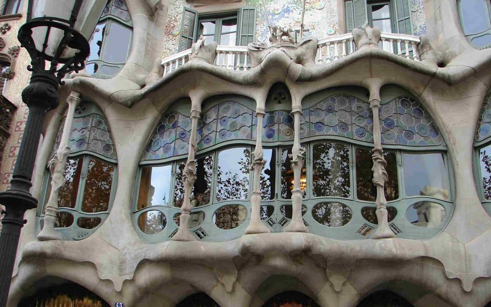 Обои для рабочего стола Балконы знаменитого дома Бальо / Casa Batllo, украшенные лепниной, на фасаде здания, рядом фигурный уличный фонарь, ахитектор Гауди, Барселона, Испания