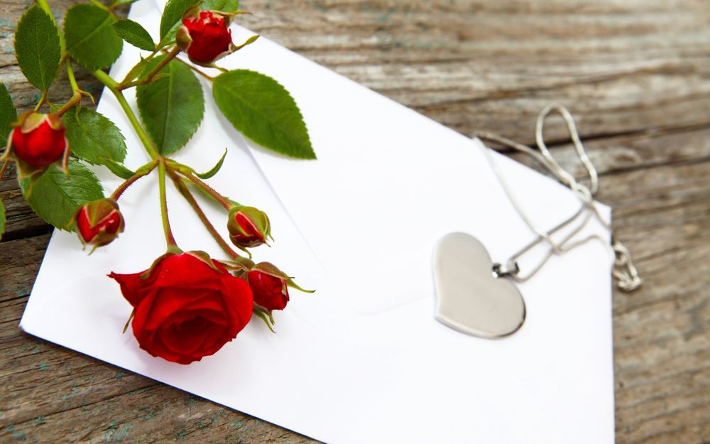 Обои для рабочего стола Кулон в форме сердца и красная роза на бумаге