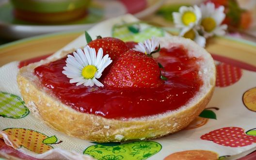 Обои на рабочий стол Кусок булки с клубничным джемом, украшенный свежими ягодами и цветами ромашки