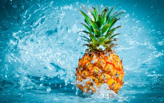 Обои на рабочий стол Ананас в брызгах воды на голубом фоне