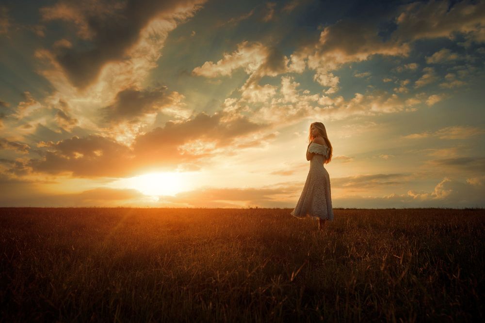 Обои для рабочего стола Девушка стоит в поле на фоне заката, фотограф TJ Drysdale