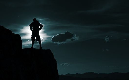 Обои на рабочий стол Силуэт мужчины на скале на фоне ночного неба и лунного света