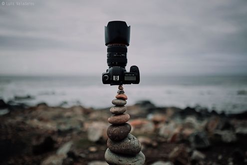 Обои на рабочий стол Фотоаппарат стоит на композиции из камней у берега моря