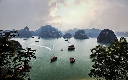 Обои на рабочий стол Корабли в бухте Halong Bay, Vietnam / Вьетнам на фоне скал в море и неба, затянутого дымкой