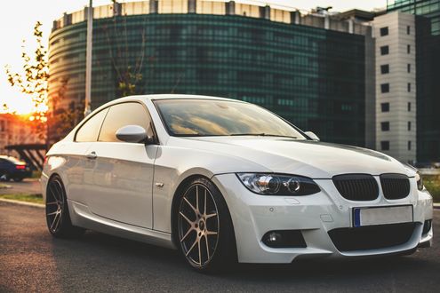 Обои на рабочий стол Белый BMW стоит на фоне здания