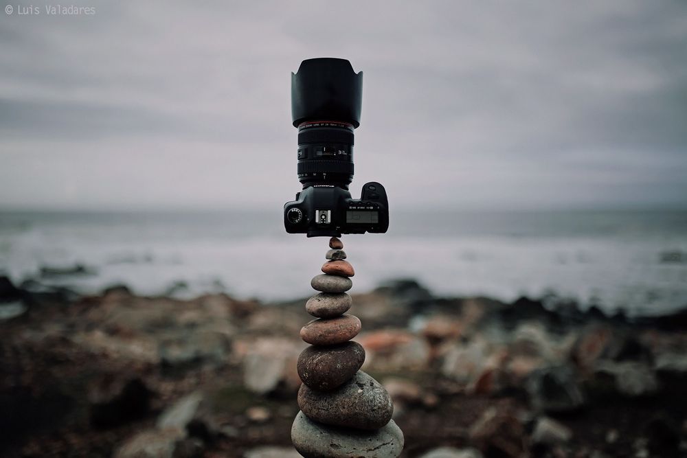 Обои для рабочего стола Фотоаппарат стоит на композиции из камней у берега моря