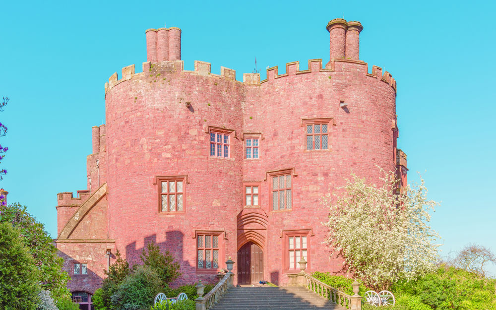 Обои для рабочего стола Башенки и каменная лестница замка Powis Castle, Welshpool, Wales, United Kingdom / Уэльс, Великобритания на фоне голубого неба, рядом цветущие заросли