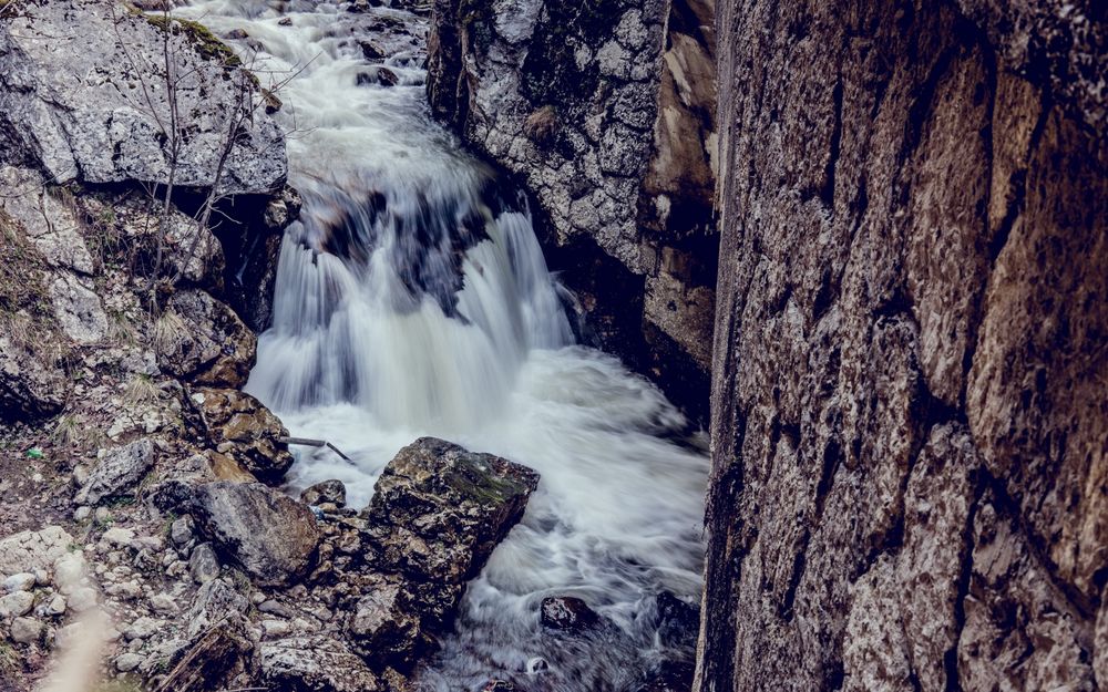 Обои для рабочего стола Поток воды с небольшими водопадами струится в каменной стремнине
