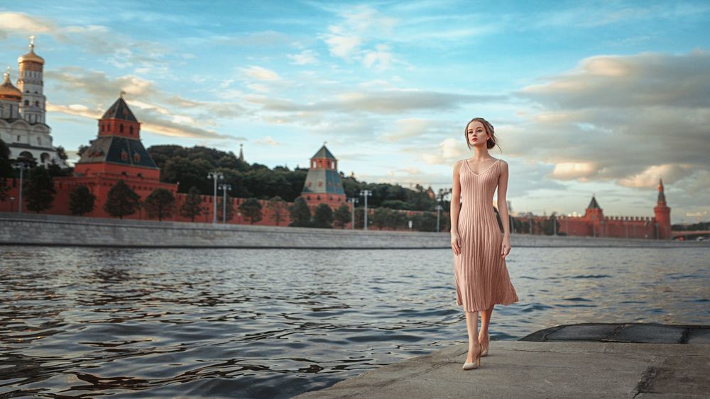 Обои для рабочего стола Девушка Мария в розовом платье стоит с реки на фоне города, фотограф Георгий Чернядьев