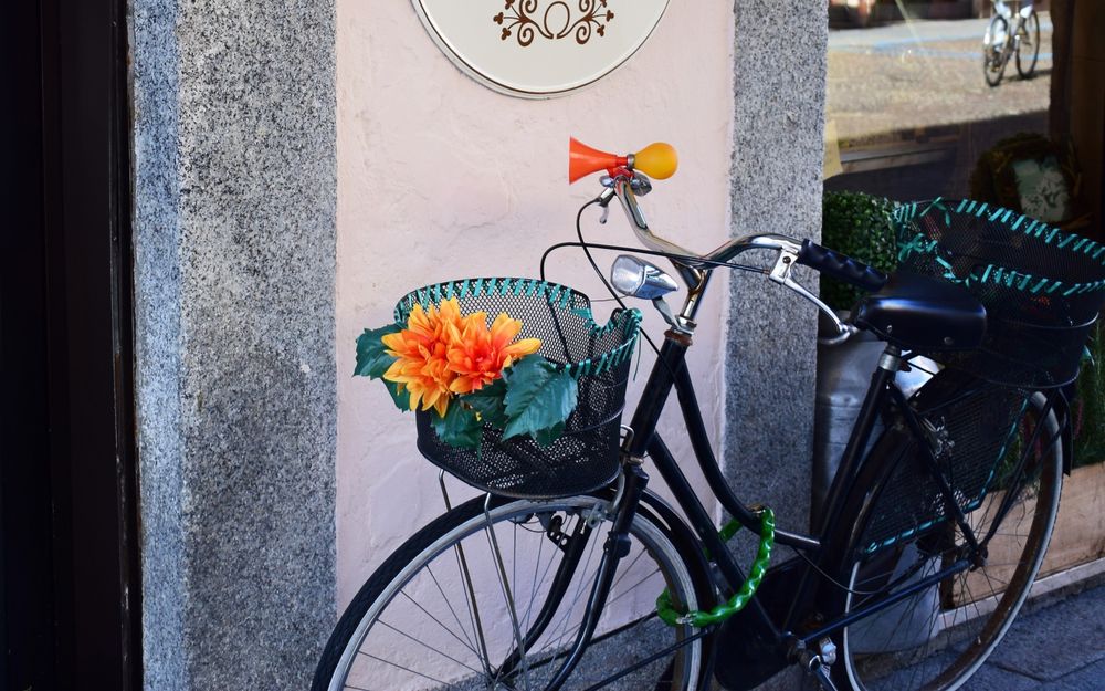 Обои для рабочего стола Велосипед, на котором прикреплена корзинка с цветами, стоит возле стены дома