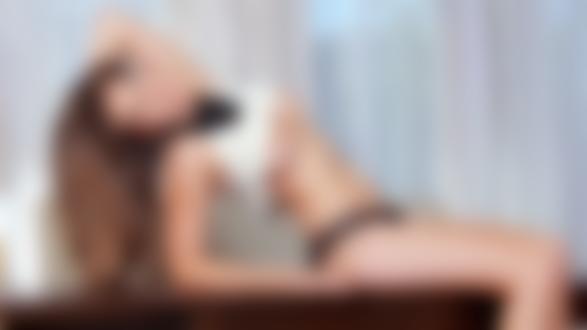 Обои для рабочего стола Модель Connie Carter с длинными волосами с украшением на шее и с приподнятой кофточкой сидит на столе