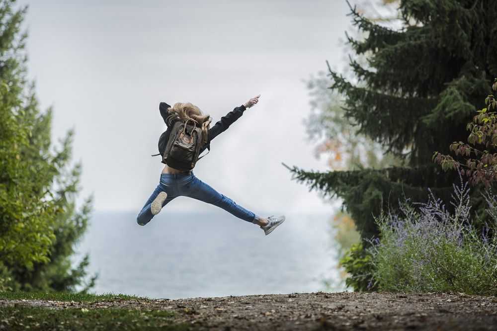Обои для рабочего стола Девушка с рюкзаком за спиной в прыжке на фоне природы, фотограф Себастьян Воортман