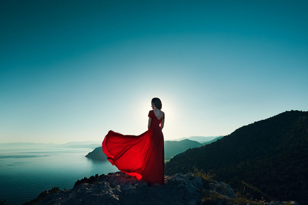 Обои для рабочего стола Девушка в красном платье смотрит на горы и море, фотограф Олег Гекман