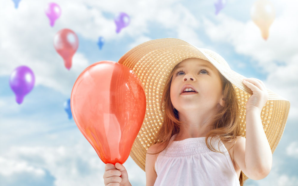 Обои для рабочего стола Девочка в большой шляпе держит воздушный шарик и смотрит в небо, где летят такие же шарики