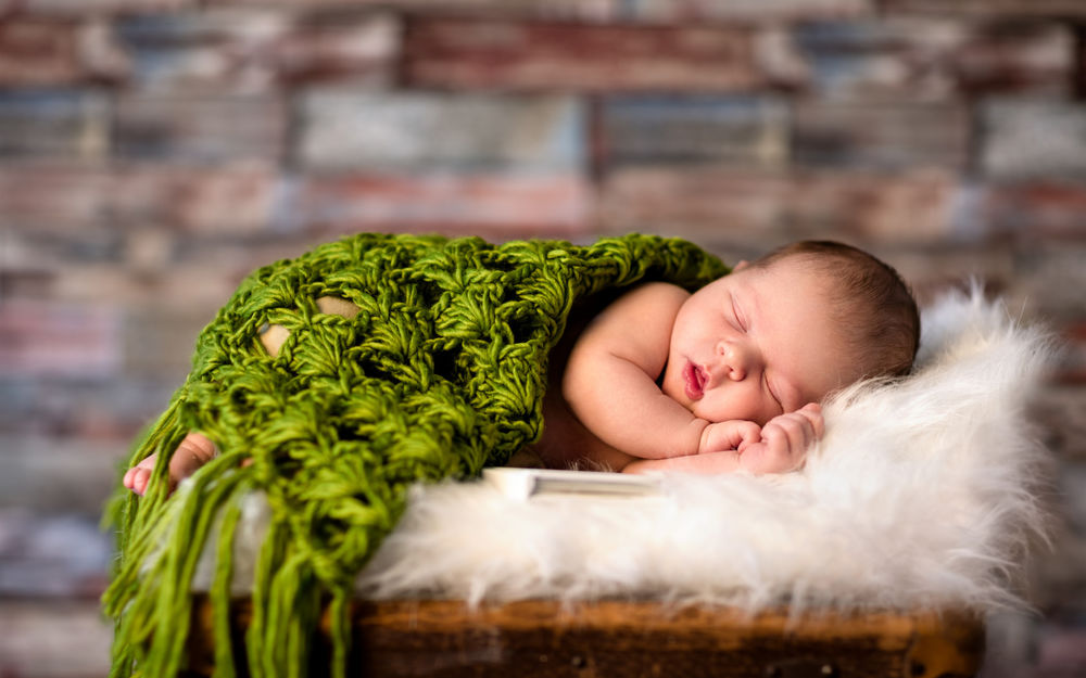 Обои для рабочего стола Младенец спит под зеленым вязаным покрывалом