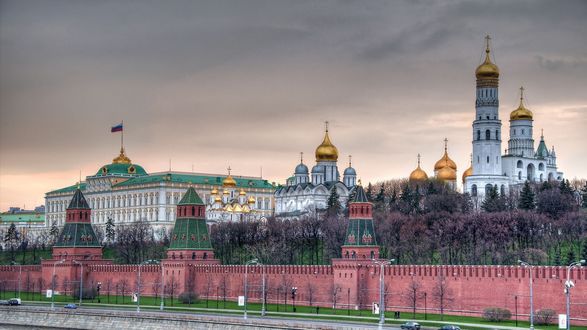 Обои на рабочий стол Кремлевская набережная Москвы реки, дворец с флагом и золотые купола Храма Христа Спасителя под ванильным небом