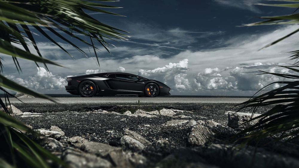 Обои для рабочего стола Lamborghini Aventador стоит на дороге на фоне неба