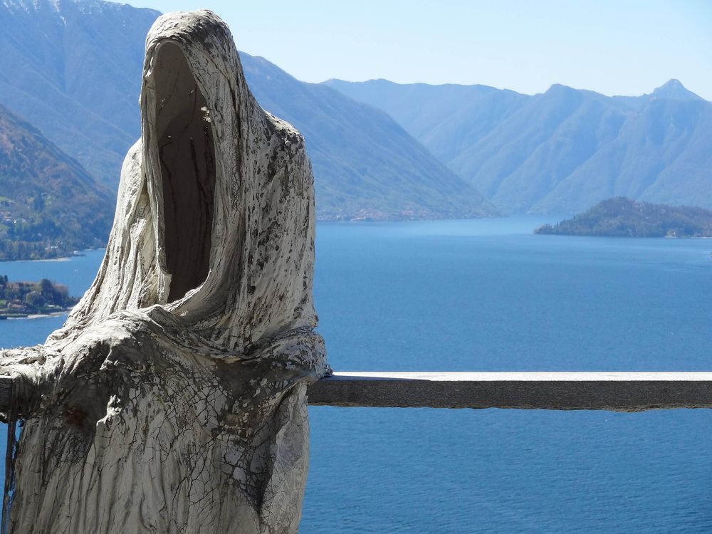 Обои для рабочего стола Мрачная статуя фигуры в капюшоне сидит на фоне озера Комо и гор в тумане, Italy / Италия
