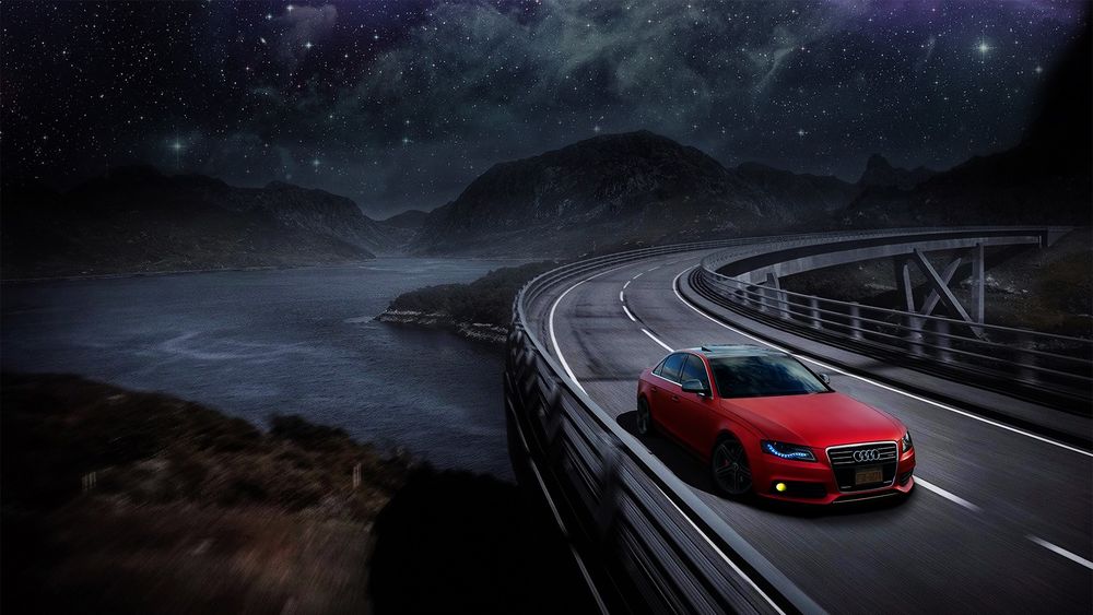 Обои для рабочего стола Красный Audi едет по дороге, на заднем плане горная река под звездным небом