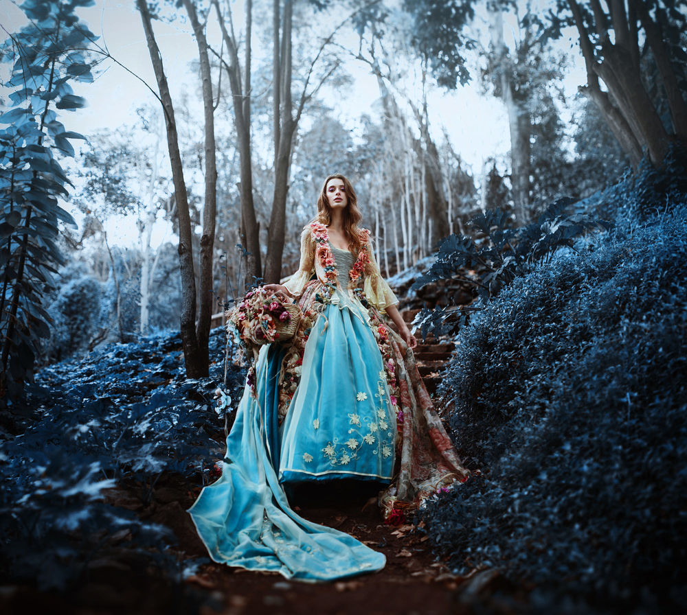 Обои для рабочего стола Девушка в длинном платье с корзиной цветов стоит в лесу, фотограф Ronny Garcia