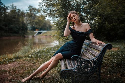 Обои на рабочий стол Модель Disha Shemetova / Даша Шеметова в черном платье сидит на лавочке у реки