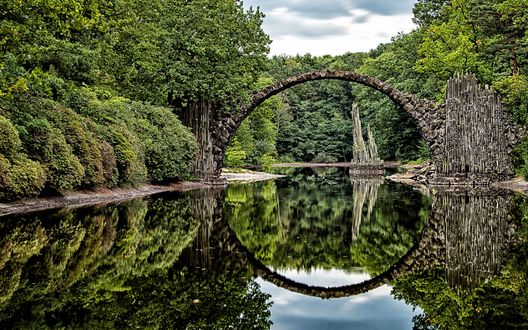 Обои на рабочий стол Полуразрушенный арочный мост Rakotzbrucke Devils Bridge in Gablenz, Germany / Дьявола Ракоцбрюке в Габленце, в Германии через реку, заросшую лесом, отражается в воде