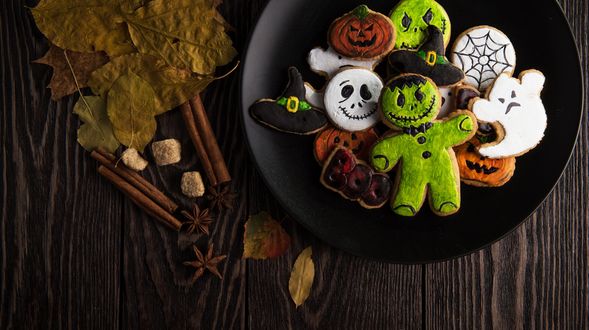 Обои на рабочий стол Черная тарелка с глазированным печеньем для Halloween, рядом сухие листья и корица
