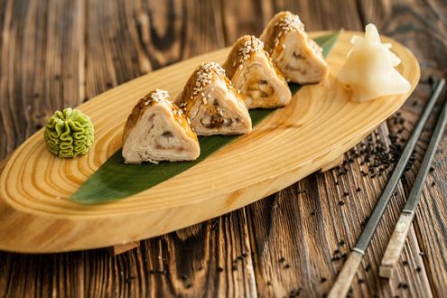 Обои на рабочий стол Японская кухня: треугольные роллы, васаби и имбирь на деревянной подставке и палочки для еды