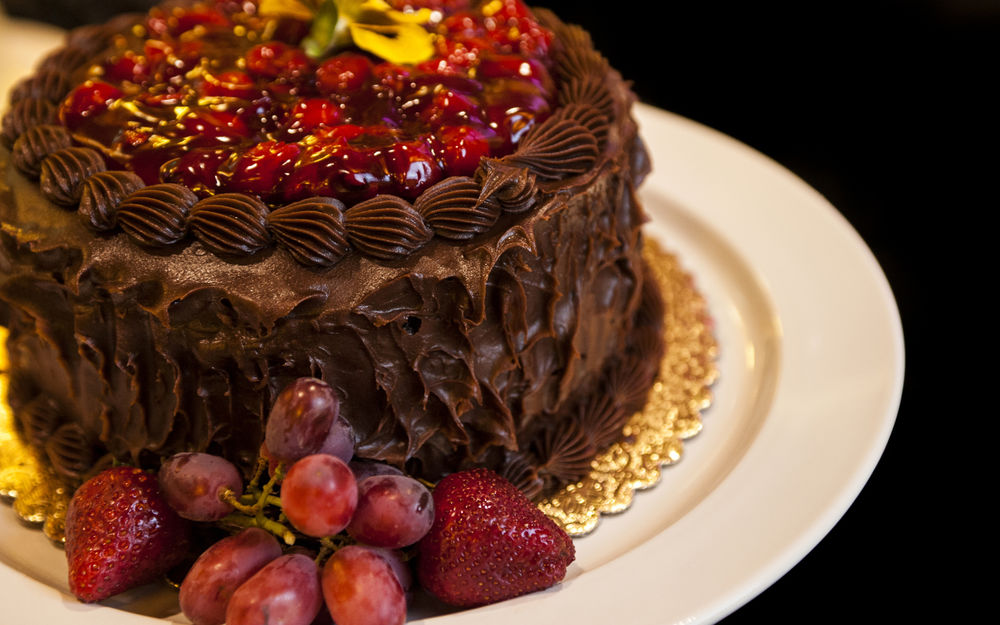 Обои для рабочего стола Шоколадный торт с кремом, украшенный свежей клубникой и виноградом