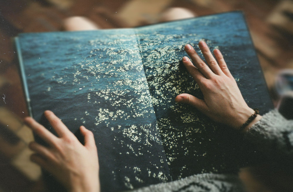 Обои для рабочего стола Книга, на страницах которой море, в руках девушки