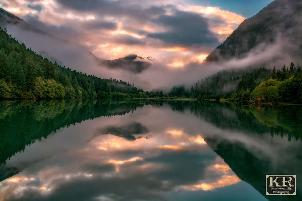Обои для рабочего стола Diablo Lake / Озера Диабло в окружении гор и зеленых деревьев, фотограф Kevin Russell