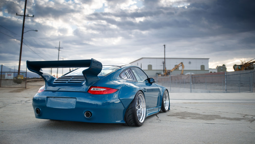 Обои для рабочего стола Porshe 997 стоит у ворот здания