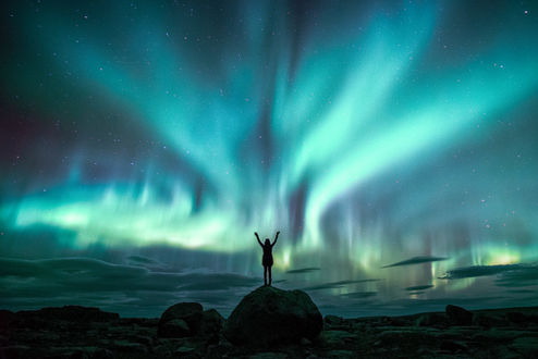 Обои на рабочий стол Девушка стоит на фоне северного сияния, фотограф Lizzy Gadd