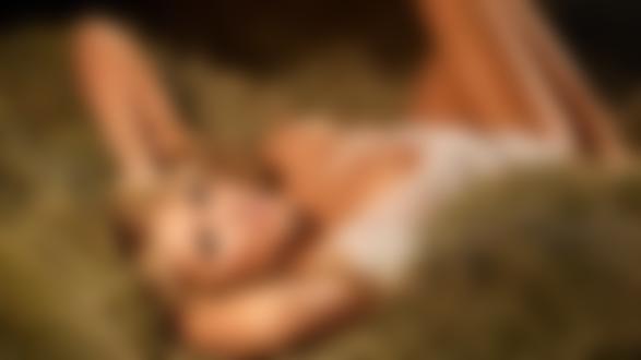 Обои для рабочего стола Симпатичная болндинка в расстегутой сорочке с обнаженной грудью лежит на сеновале