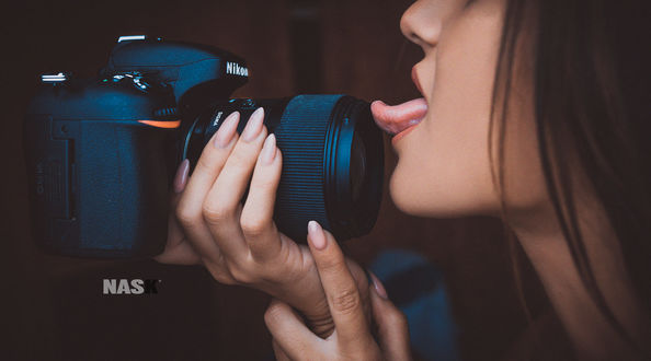 Обои на рабочий стол Девушка с фотокамерой в руках показывает язык, by Nask Photo