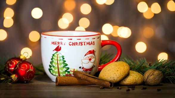 Обои на рабочий стол Кружка с надписью Merry Christmas / Веселого Рождества, печенье, палочки корицы и новогодние шарики на столе на фоне боке