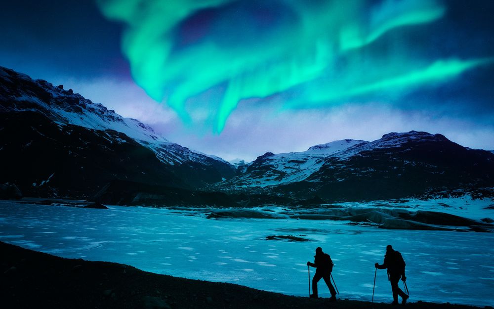 Обои для рабочего стола Лыжники любуются северным сиянием в горах Iceland / Исландии