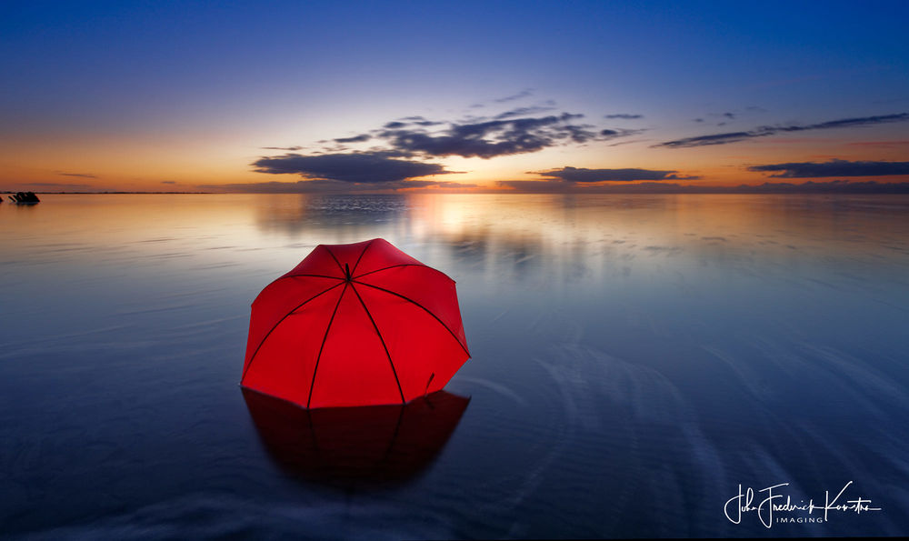 Обои для рабочего стола Красный зонт лежит в воде, фотограф John Kamstra