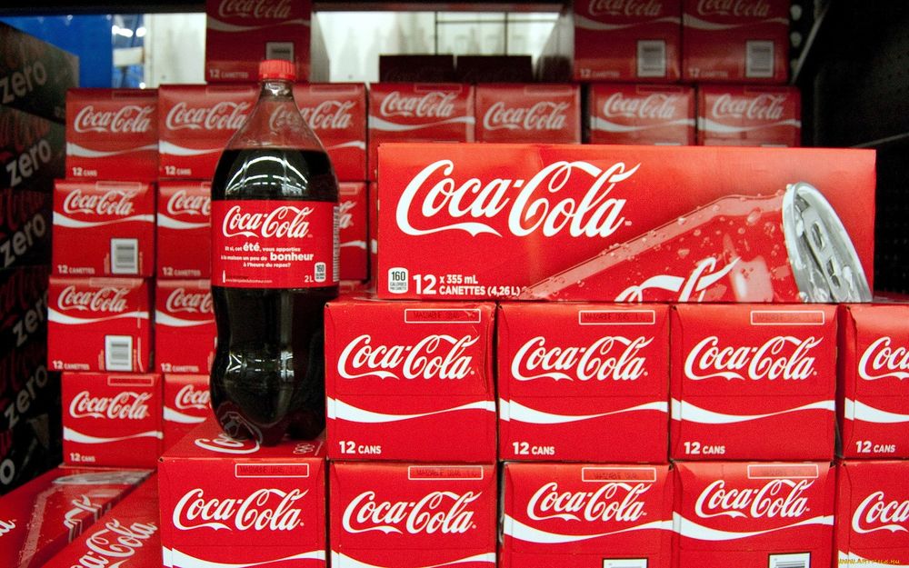 Обои для рабочего стола Бутылка кока-колы / coca-cola стоит на коробках с напитком