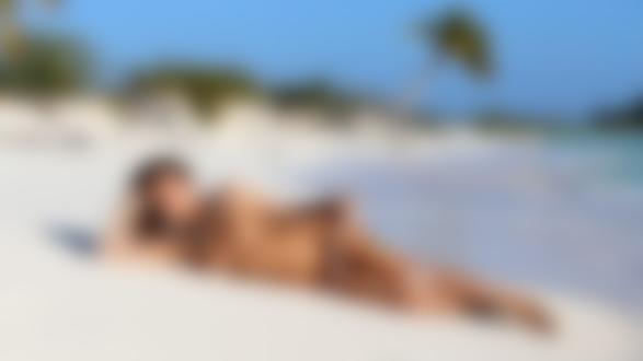 Обои для рабочего стола Российская модель Katya Clover / Катя Кловер (настоящее имя Екатерина Скаредина) с ожерельем на шее позирует лежа на песчаном пляже