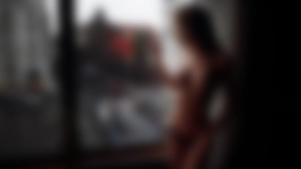 Обои для рабочего стола Стройная обнаженная девушка позирует стоя у окна с видом на город. Фотогаф Иван Горохов