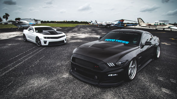 Обои на рабочий стол Chevrolet Camaro и Ford Mustang на дороге в аэроклубе