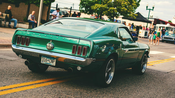Обои на рабочий стол Темно-зеленый Mustang на дороге небольшого городка