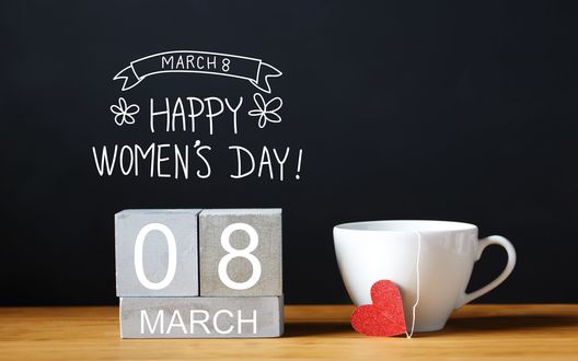 Обои на рабочий стол Чашка с сердечком на ниточке стоит рядом с фразой 8 March, Happy Womans Day / 8 марта, Международный женский день на темном фоне